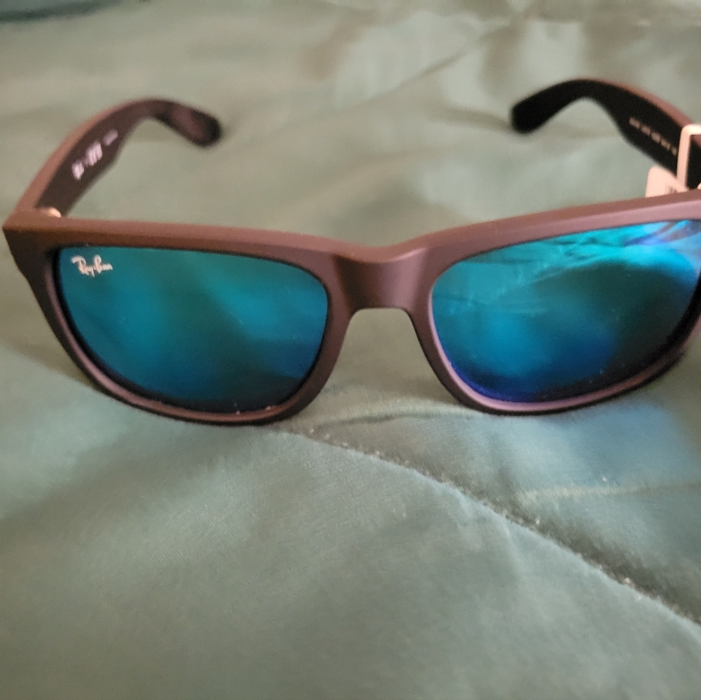 Beautiful black Ray-Ban sunglasses with a blue and green tint on the front
